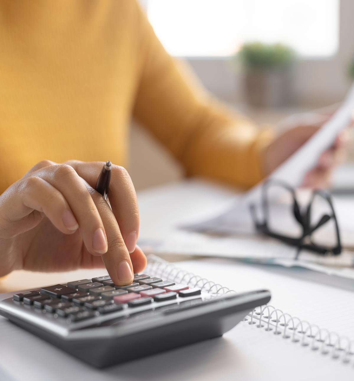 Person using calculator and reviewing documents.